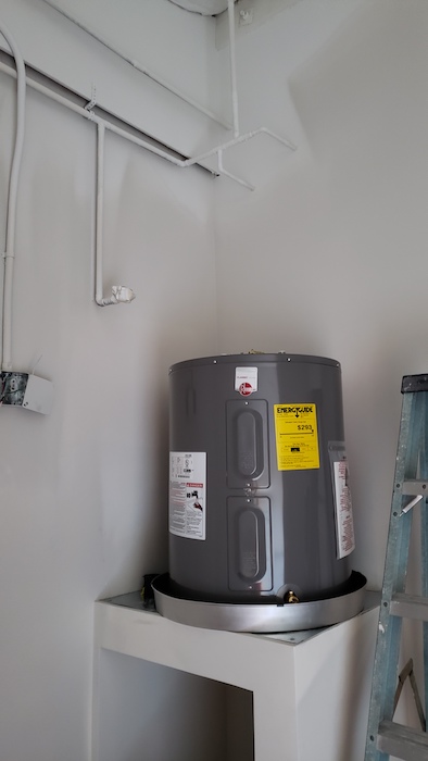 Showing water heater stand over mop sink with drywall.